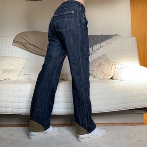 Mörkblå Jeans med detaljer - Säljer dessa coola mörklblå jeans med bruna detaljer vid hälarna! Storleken är W34L32, 90cm midja och 75cm innerbenslängd! Jag på bilderna är 172cm lång och brukar ha storlek 38/W28/S-M❤️