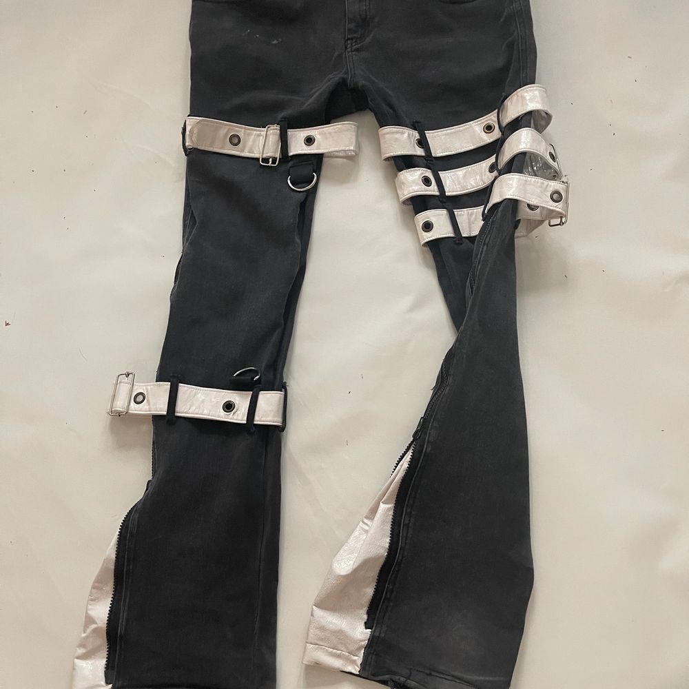 Svrta bootcut byxor med vita läder spännen runt om, där det är bootcut kan man dra ner en dragkedja och där finns det vitt läder de. Så snygaaaaa. . Jeans & Byxor.