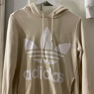 Adidas hoodie  - Biege adidas hoodie med vit text på framsidan 