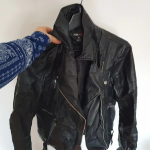 Faux läderjacka - Skinnjacka i fejkläder som är för liten på mig. Några hål i kragen på ena sidan efter coola pins därav priset.