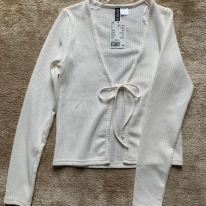 H&M tröja - Säljer denna helt oanvända koftan från H&M. Man kan knyta upp snörena där fram! Det är storlek xs och jag köpte den för 99kr men säljer för 50kr. Frakten ingår inte men jag kan mötas upp i Göteborg:)