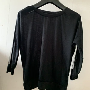 Tröja - En svart tröja med genomskinlig detalj vid ärmen 