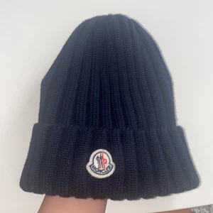 Moncler mössa  - Säljer min mörkblåa moncler mössa då den inte har och kommer inte komma till användning. Den är köpt på Farfetch och dustbag medföljer. Om ni vill att jag ska skicka den tillkommer frakt (66kr)