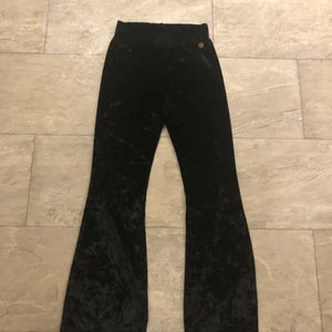 Svart utsvängda byxor i sammet  - Svarta utsvängda byxor i ett sammets liknande material. Säljer pågrund utav att de är för små.