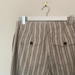 OUR LEGACY SERVICE TROUSER strl 36 oanvända - Beigefärgade bomulls- och virgin wool blandad randig byxa med raka ben från Our Legacy. Hög midja, bälteshällor, fickor i sidorna och bak samt dold gylf. Helt oanvända och i nyskick! Storlek 36. Inköpta i vintras för ca 2000 kr.  Skickas eller hämtas på Södermalm eller i Tyresö.