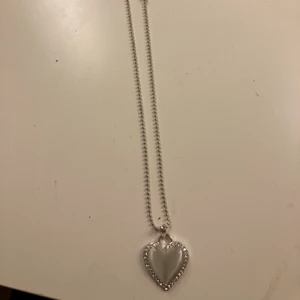 Ett halsband som är ett silvrigt  - Ett halsband som är silvrigt med ett hjärta på och detta halsband är ganska långt 