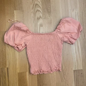 En orange tröja, storlek XS - En orange topp med ett ovanligt material på tröjan. Puffar vid axlarna/ärmarna. Aldrig använd och köpt från Gina tricot. 