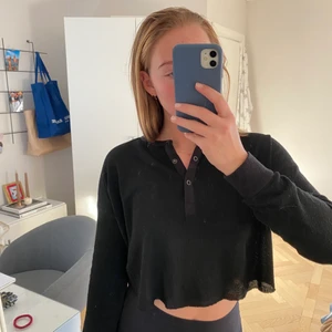 Kort Svart topp från Urban Outfiters - Säljer denna snygga svarta, kortare, långärmade topp. Den har muddar på ärmarna och knappar vid halsringningen. Den är i ett lite refflat material och inte använd på väldigt länge. Storleken är XS. Frakt tillkommer om inget annat är överenskommet 😊