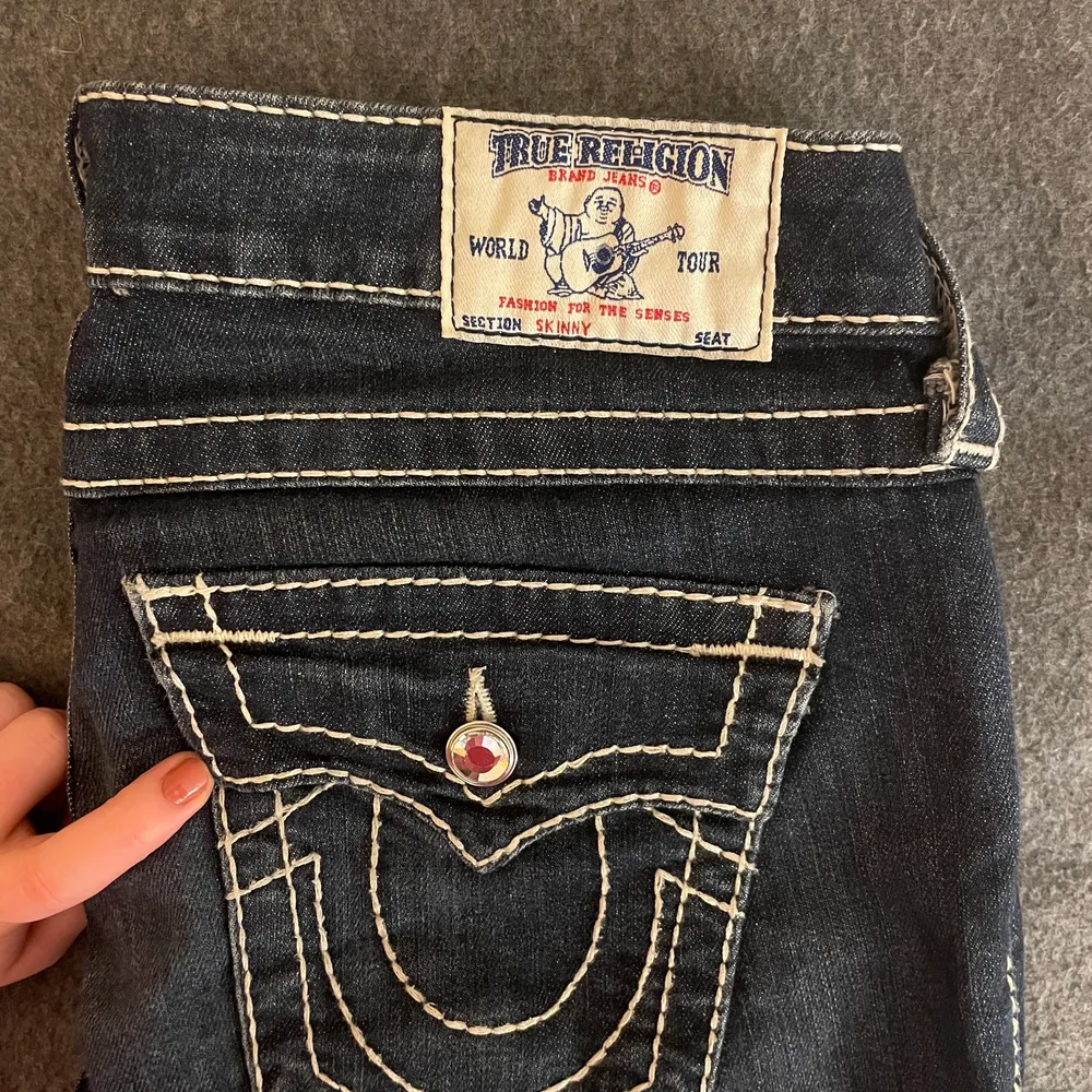 Äkta True Religion jeans som är lågmidjade och raka längst ner - snyggt att matcha med t.ex. stövlar! Använda typ 1 gång så de är som nya. Knapparna är diamanter. Jag är 164 cm och har S i byxor men de passar oxå nån som är några cm längre . Jeans & Byxor.