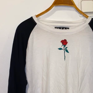 Tröja - Långärmad tröja med en ros på bröstet som detalj. Longfit. Använd ca 5/6 gånger. Storlek L men passar perfekt på storlek M då den är lite tajt i storleken.
