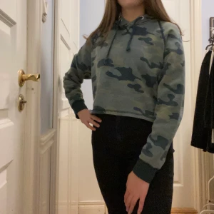 Hoodie  - Grön millitärmönstrad croppad hoodie. Storlek M men mer son en XS-S. Köparen betalar frakten. 