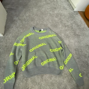 Tröja  - En grå stickad tröja där det står ”original” i neon gul färg, tröjan har använts en gång därför säljer jag den 