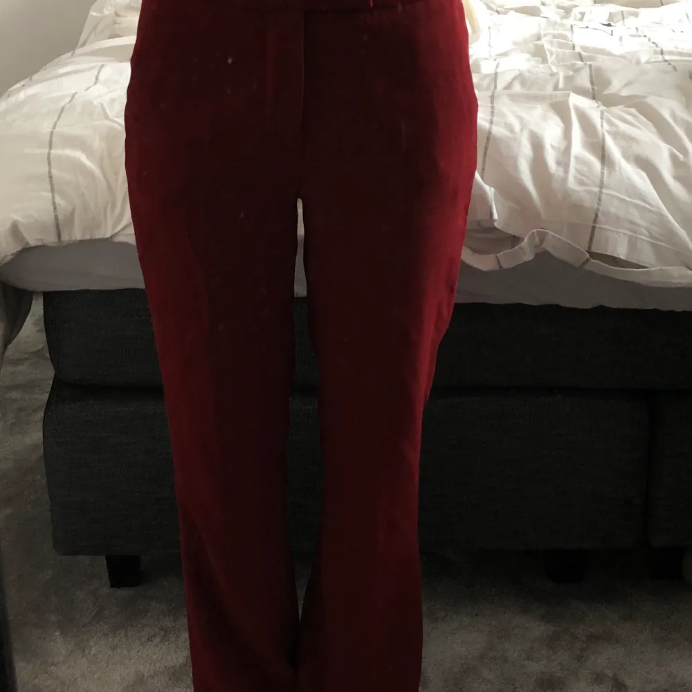 Vinröda kostymbyxor i en utsvängd modell. Lågmidjadd, storlek xs. Dom är uppsydda men är bra längd på mig som är 163cm.. Jeans & Byxor.