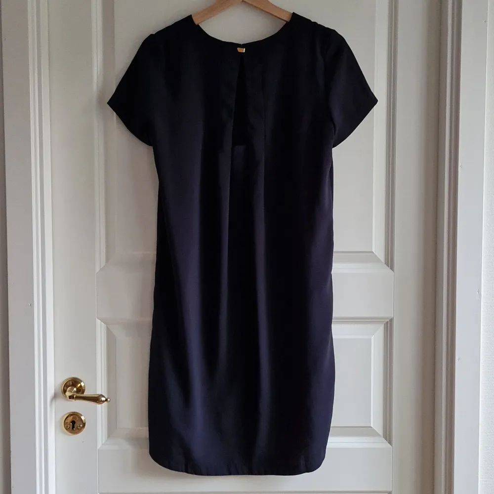 Navy blue dress from H&M with a cutout on the back. Golden fastening. Total length 88 cm.. Klänningar.