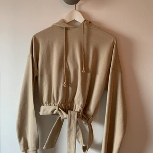 Kort hoodie - Supersnygg och stilren hoodie! Kortare i modellen med en knytning framme i midjan. Aldrig använd och anledningen till det är att den är väldigt tajt i halsen, så jag med stort huvud måste offra både smink och hår när jag ska få på mig den😂