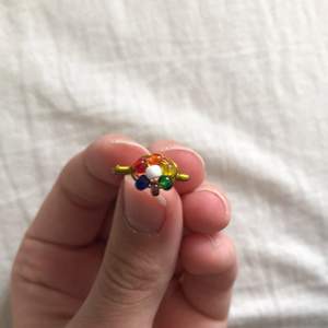 En handgjord ring med regnbågsfärgad blomma på. Väldigt fin och bra kvalite. Jag kan ändra färg på pärlorna, ändra storlek på ringen och ändra till roséguld eller silver istället för guld efter önskemål. Det är bara att kontakta mig. 