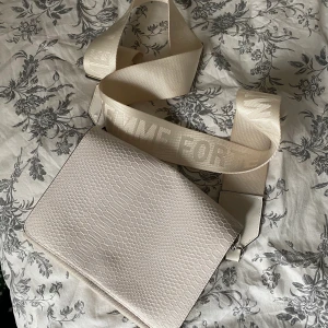 Krämvit axelremsväska - Krämvit axelremsväska i bra skick! Användts ett fåtal gånger.