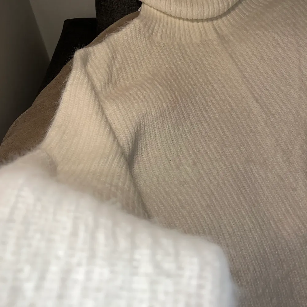 Fluffigt vit croppad stickad tröja. Hög polokrage och på mig (har långa armar) lite kortare ärmar. Väldigt skönt material. . Stickat.
