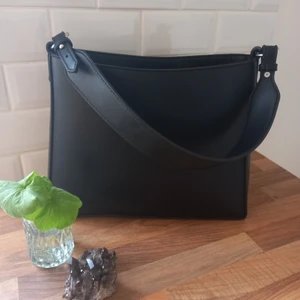 Oanvänd vegansk handväska Green Laces - En fantastiskt fin och oanvänd väska I veganskt mjukt konstskinn, från det danska märket Hvisk.Väskan är gjord av återanvänt material och producerad under kontrollerade förhållande. Väskan har många bra och praktiska fack.  Mått: Höjd 25 cm, Längd 31,5 cm, Djup 11 cm   Nypris: 1200 kr