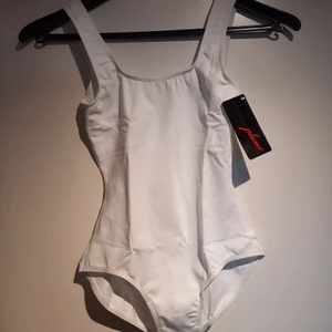 Helt ny vit Balettdräkt - Jättefin balettdräkt som aldrig använts. Den är mycket stretchig och i originalförpackning med lappen kvar. Material: 88% Cotton och 12% Spandex. Den har en inbyggd BH, vilken syns på tredje bilden där dräkten är vänd ut och in. Jag säljer en likadan dräkt i storlek M, ifall denna skulle vara för liten. 😊 Skriv till mig vid frågor eller funderingar💕