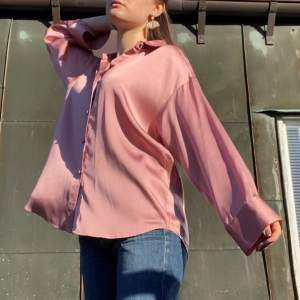 Helt underbar rosa skjorta i fantastiskt lätt och skönt satinliknande material från Zara. Skjortan är något glansig i materialet och har fina klädda knappar fram och på ärmarna. Otroligt trendig just nu och passar till perfekt till sommaren lite uppknäppt med en bralette under eller som en overshirt med ett linne under. Modellen är slutsåld. Storlek S. Dock är designen oversized, vilket gör att den passar allt ifrån XS-M beroende på hur man vill att den ska sitta. Mitt pris 250kr. 