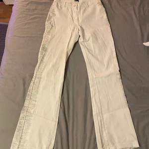 Vita byxor  - Vita högmidjade byxor! Längs kanten på båda sidorna är det typ glitter och dom är lite stretchiga. Midjemått 76cm💕💕 innerbenslängd 78cm