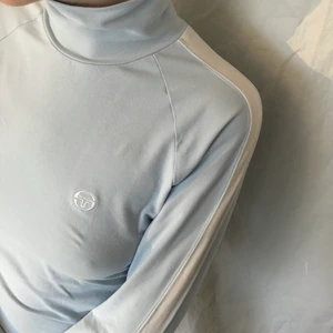 Polotröja - Så cool vintage turtleneck i ljusblått och vitt från märket Sergio tacchini. Långärmad med vita detaljer på armarna. Mjukt stretchigt bomullstyg, I princip nyskick.Går att vika upp som på bild ett eller ha instoppat i typ en vit tenniskjol eller med jeans. Färgen är närmast bild 2!!