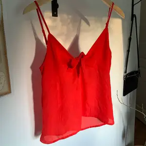 Ett supergulligt rött linne från H&M i strl Small. Skulle säga att den är lite blusaktig i materialet samt har en knytning framtill som går att variera. Använd ett fåtal gånger så den är i fint skick!     Köpare står för eventuella fraktkostnader. 