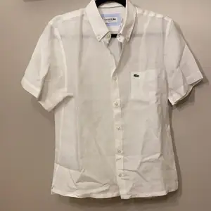 Vit kortärmad skjorta från Lacoste, 100% Linnen. Stl. 40. Regular fit. Ordinariepris 650kr. Säljer för 400 pga ej rätt Stl. 