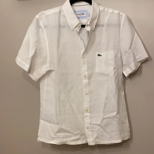 Lacoste skjorta - Vit kortärmad skjorta från Lacoste, 100% Linnen. Stl. 40. Regular fit. Ordinariepris 650kr. Säljer för 400 pga ej rätt Stl. 