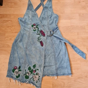 Omlottklänning - Omlottklänning i jeans med broderier. Aldrig använd. Från djur och rökfritt hem. Kan skickas mot fraktkostnad 