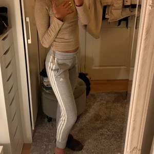 Adidasbyxor  - Adidas mjukis byxor. Grå med vita sträck. Använda ett antal gånger men fortfarande i bra skick. Skulle passa de som är 170cm och kortare.