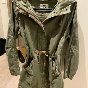 Militärgrön jacka  - Grön jacka från Cubus i storlek XS. Sparsamt använd. Finns att hämta i Saltsjöqvarn i Nacka, jag kan också mötas i stan. 