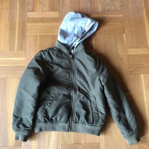 Jacka stl 134 - Grönjacka i stl 134. Man kan även ta av luvan om man inte vill ha den på. 