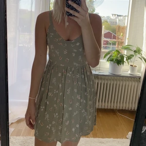 Superfin grön klänning  - Superfin grön klänning från pull and bear, oanvänd; prislapp kvar på klänningen. Storlek M men passar S bättre. Rosa/vita blommor. Nypris 250kr. 