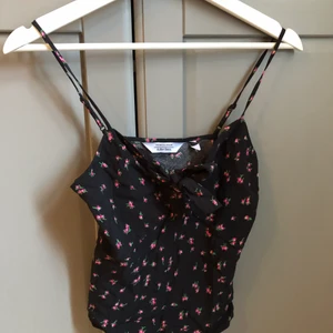 Linne från & other stories - Blommigt linne i färgerna svart och rött från & other stories. Axelbanden är justerbara och linnet har en justerbar knut vid bysten. XS/S