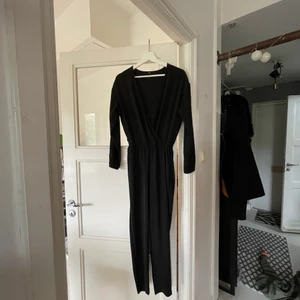 Svart byxdress strl 34  - Jumpsuit med fin urringning eller fäst med en knapp som medföljer i köpet.   Strl 34