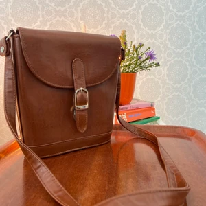 Väska  - En brun skinnväska med gulddetaljer och långt axelband . 