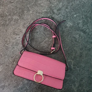 Liten väska, från H&M, oanvänd. - En liten väska från h&m org pris 250 kr, rosa med guld detaljer, fake krokodil skinn💕. Helt oanvänd och i jätte bra skick. Går att ha som hand och axelväska.😊frakten står köparen för!