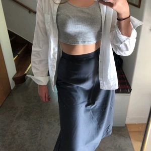 Kjol - INTRESSEKOLL! Silkesaktig mörkgrå kjol från H&M. Använd en gång. Storlek 36. Finns tecken på använding (se bild 3) ganska långt ner på höger sida, väldigt diskret och det märks inte när man bär kjolen.