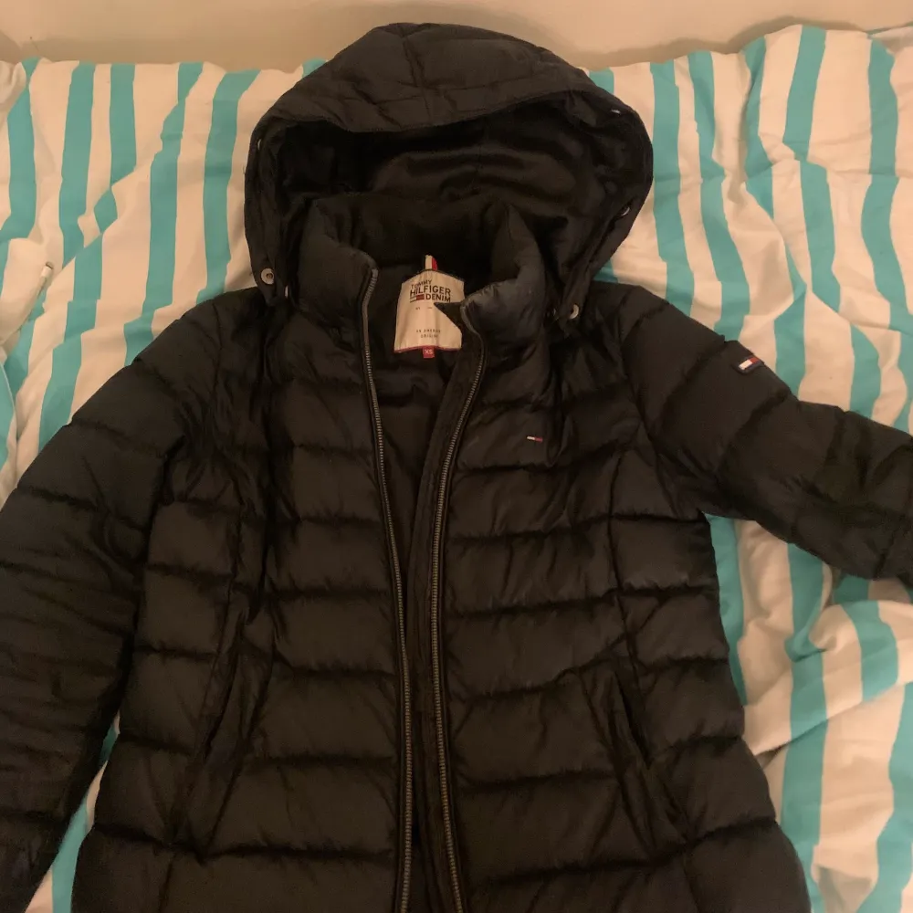 Svart Vinterjacka från Tommy hilfiger. Storlek xs. Jackan är i dun. Använd men bra skick, däremot är det en liten trasig bit (vet inte vad jag ska kalla det men kolla på andra och tredje bilden) över vänstra fickan samt vid vänstra armen (detta pga en pin). Dessa syns dock inte alls på långt håll och har inte orsakat några problem för mig. Nypris 2200 kr. Finns även fluff till jackans luva. Skriv för mer bilder . Takit.