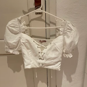 Vit topp - Jättesöt milkmaid topp med puffarmar och snörning där fram!! Den har även en dragkedja på sidan som inte syns när den är stängd! Jättesöt och härlig sommartopp som jag bara har använt 1 gång eftersom den var lite liten för mig! 