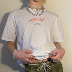 Vit graphic tee Wacay hållbar aprikos rosa turkos mörkgrön text  - Vit oversized graphic tee från det svenska hållbara märket Wacay med litet tryck på bröstet i aprikos och en mörk turkos färg som lyder ”Wacay, saturday slack, saturated sunday” i den underbaraste fonten 🪴 Jag älskar inte bara hur detta är det perfekta basplagget som går att matcha med alla möjliga byxor, accessoarer och skor utan även de softa färgerna som gör att t-shirten går att stylea med ännu fler plagg! Som i 3e bilden har jag parat ihop den med en väst i samma färgskala för en mer unik look som ändå har en röd tråd!