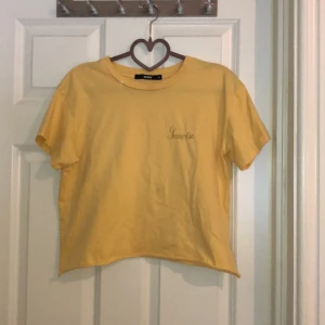 T-shirt  - Gul T-shirt med liten text på bröstet