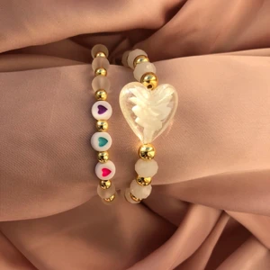 Armband - Jag säljer dessa otroligt vackra armband 🤍 De är så himla fina och passar till nästan allt! Det stora hjärtat är en glaspärla med guldfärgade hematit pärlor. Armbanden är gjorda av elastisk tråd så storlekarna kan variera, men måtten är gjorda ifrån en S/M                                                                                                      Det armbandet som har glashjärtat kostar 70 och den andra kostar 60 eller båda för 120+  frakt