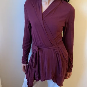 Vinröd kofta med band runt midjan - Lång fin kofta med band runt midjan i färgen vinröd. Koftan är fortfarande i bra skick och kan användas både för sommaren och vintern. Den går både att styla upp och ned, göra det till mer vardags eller piffa till det lite mer. 