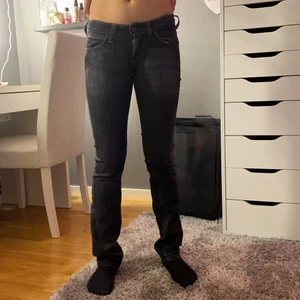 Lågmidjade urtvättade svarta jeans - Märket på byxorna är Lee och är i en urtvättad svart färg. Byxorna är i prefekt skick och är i storlek W25 L31, vilket motsvarar ungefär XS. Modellen på byxorna är Maddox Modellen är 166 cm 