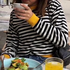 Randig sweatshirt  - Säljer denna långarmade lite tjockare tröja från Bershka. Den är svart och vitrandig med gula muddar. Jag är 165 och har storlek S