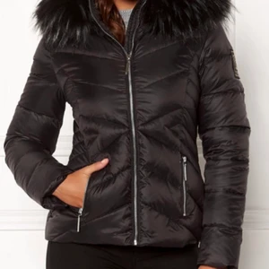 Chiara Forti Dunjacka - Dunjacka i stl 34 från Chiara Forthi Milano. Midjekort, figursydd modell i 80% dun och 20% fjäder, fuskpäls runt huvan som kan knäppas bort med knappar. Knappt använd i mycket fint skick. Nypris 1895kr