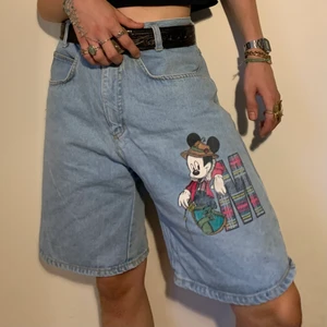 Ljusa retro oversized Musse pigg shorts - Vintage oversized Disney shorts med Musse Pigg tryck och bokstaven M i plaid mönster 🍓Det jag älskar mest med dessa shorts är inte bara de sjuka 80s vibesen och den perfekta washen utan hur lätta de är att stylea med vad som helst, ett vitt ribbat linne eller svart baby tee för att låta fokuset vara på byxorna med en plaid skjorta över för att matcha eller en enfärgad tröja i någon av färgerna från trycket! Det är de perfekta basic shortsen men med en unik detalj! Midjemått 84 cm, byxlängd 51 cm